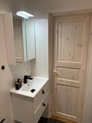a bathroom with a sink and a mirror and a door at TaaliHomes Kuremaa ridaelamu järve kaldal - saun hinnas in Kuremaa