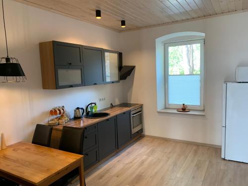 a kitchen with black cabinets and a table and a window at TaaliHomes Kuremaa ridaelamu järve kaldal - saun hinnas in Kuremaa