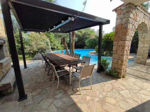 a wooden table and chairs under a black pergola at Villa A CASA DI FICU proche d'Ajaccio avec piscine et jacuzzi in Peri