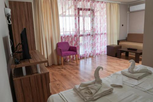 a living room with a bed and a tv and a couch at Akladi Family Hotel in Chernomorets
