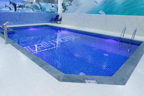 Alain Hotel Apartments Ajman في عجمان: حمام سباحة كبير مع أرضية من البلاط الأزرق