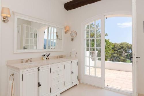ein weißes Bad mit einem Waschbecken und einem Fenster in der Unterkunft Luxury 5 bedroom, 4 bathroom villa in Antibes in Antibes
