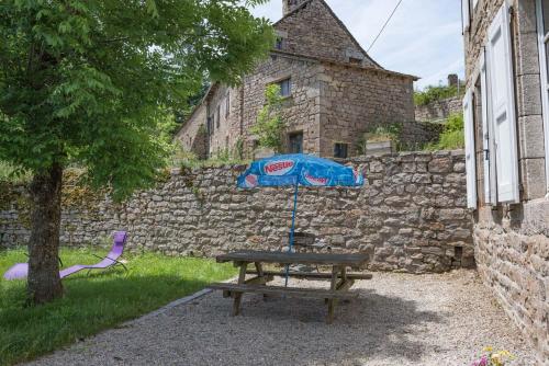 a picnic table with an umbrella next to a stone wall at Village de gîtes de Sainte-Lucie in Sainte-Lucie