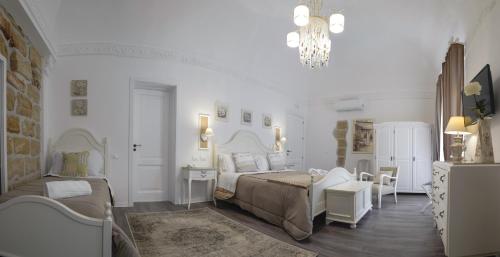 a white bedroom with a bed and a chandelier at TAM Vacanze B&B in Cinisi