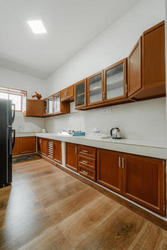 a large kitchen with wooden cabinets and a refrigerator at Sri Construction Circuit Bungalow in Batticaloa