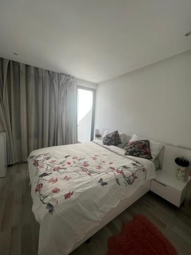 - une chambre blanche avec un grand lit fleuri dans l'établissement Studio luxueux et contemporain, à Casablanca