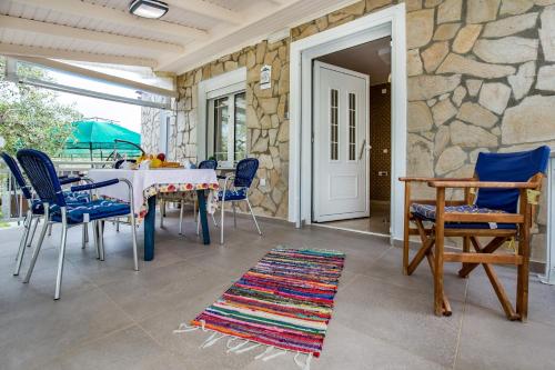 Kiriakos Holiday Home في أستريس: غرفة طعام مع طاولة وكراسي وجدار حجري