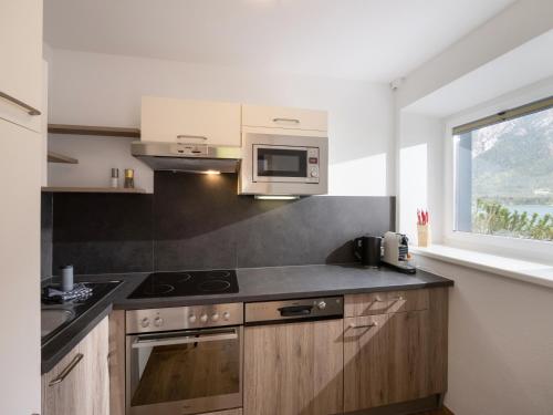 a kitchen with a stove and a microwave at Appartements Am Achensee in Pertisau