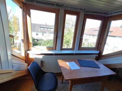 einen Tisch und einen Stuhl in einem Zimmer mit Fenstern in der Unterkunft Wohnung für 2 Personen in Villingen-Schwenningen