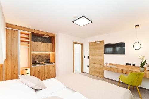 a bedroom with a white bed and a green chair at Medirooms Apartments in Feldkirchen bei Graz