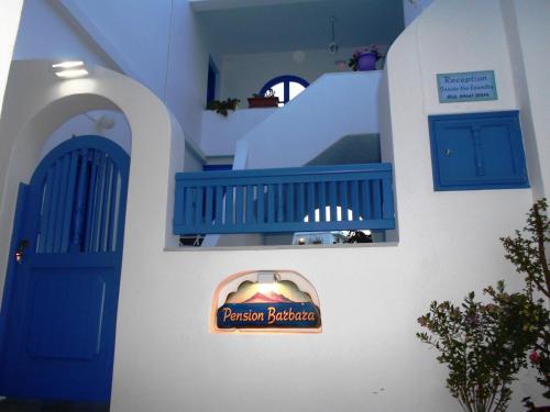 ein Schild an der Seite eines Gebäudes mit blauer Tür in der Unterkunft Pension Barbara in Katápola