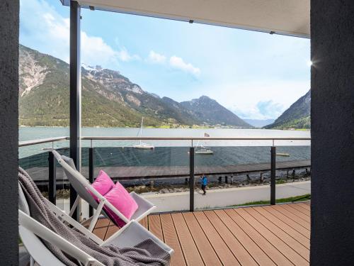 a deck with a chair and a view of the water at Appartements Am Achensee in Pertisau
