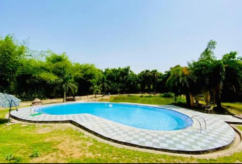 uma grande piscina num quintal com árvores em Lohagarh Corbett Resort em Belparāo