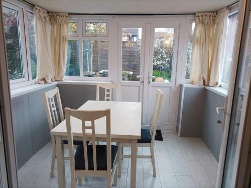 comedor con mesa, sillas y ventanas en Very Peaceful Semi Detached Home Stoke on Trent en Rough Close