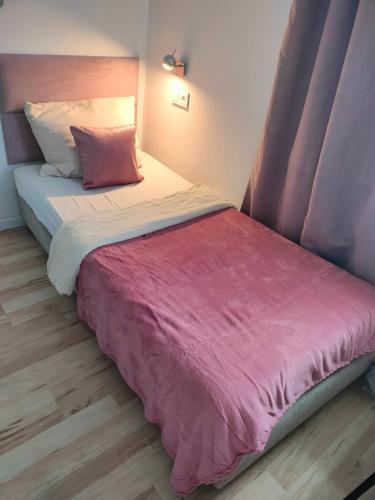 a bedroom with a bed with a pink blanket at Hostel 11 in Kozienice