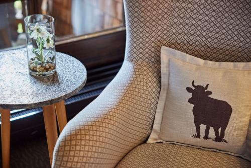 a pillow with a cow on it sitting on a chair at Parkhotel Oberstaufen in Oberstaufen