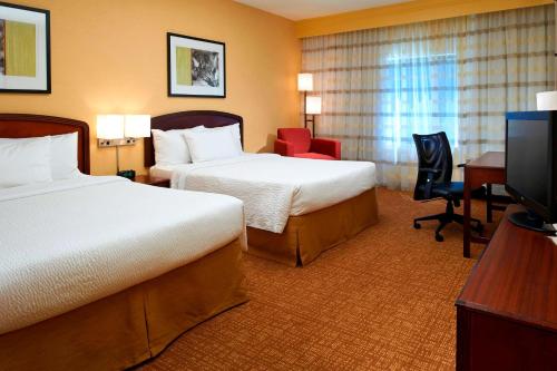 a hotel room with two beds and a desk and a television at Sonesta Select Chicago Elgin West Dundee in Elgin