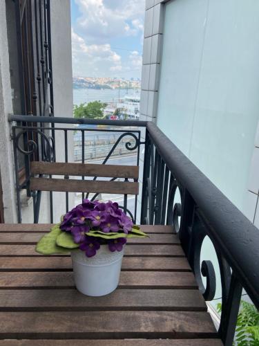 un banco sentado en un balcón con flores púrpuras en Galatolia Suites, en Estambul