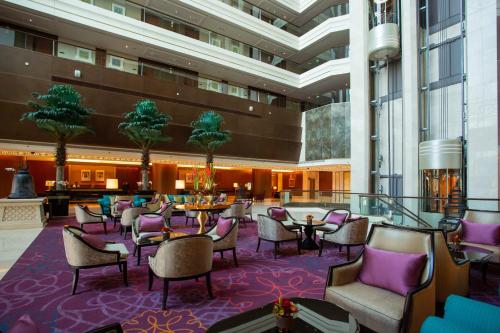 a lobby with tables and chairs in a building at Dusit Thani Abu Dhabi in Abu Dhabi