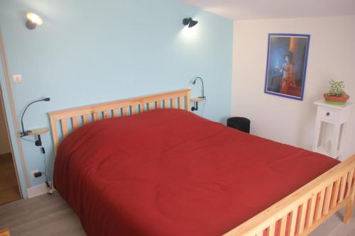 1 dormitorio con cama de madera y manta roja en Gite Moulin de Roc en Armillac