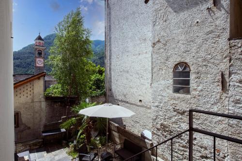 a white umbrella sitting on a balcony next to a building at Residenza La Serenata - Happy Rentals in Cavigliano