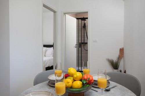 a table with a bowl of fruit and glasses of orange juice at Apartments and rooms Jakić in Medulin