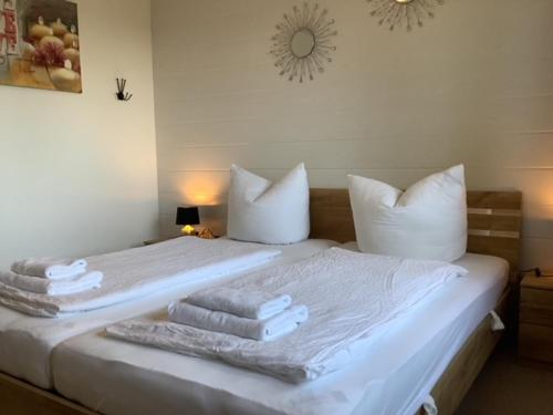 - une chambre avec un lit blanc et des serviettes dans l'établissement Blockhäuser Fewo4 Harzblick, à Braunlage
