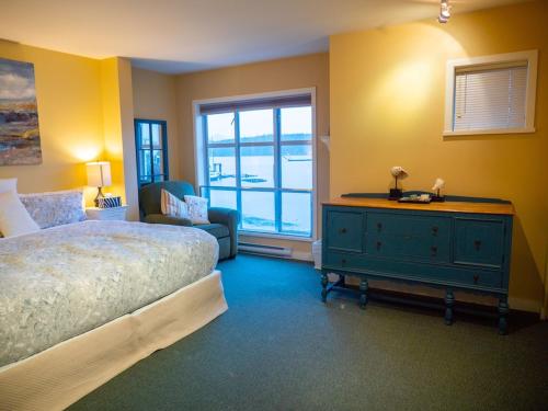 1 dormitorio con 1 cama, 1 silla y 1 ventana en Waterfront View of the Inlet, Short Walk to Town en Tofino
