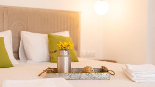 a tray with a vase with yellow flowers on a bed at Pamina Mare in Nea Skioni