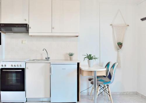 een keuken met witte kasten en een tafel en stoelen bij “Shiny” sea view apartment at Istron in Agios Nikolaos