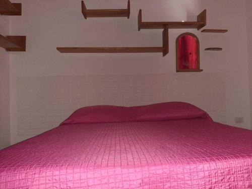 um quarto com uma cama rosa num quarto em Trilocale Serra Li Lioni - Sassari em Sassari