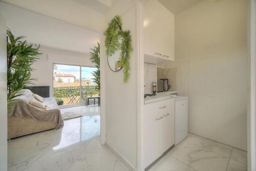 une cuisine avec des armoires blanches et un salon dans l'établissement STUDIO LUMINEUX 200 m DES PLAGES A0B192, à Cannes