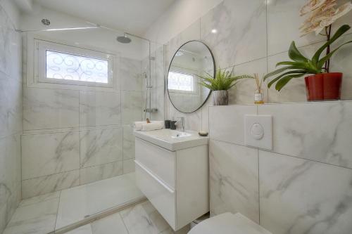 une salle de bain blanche avec un lavabo et un miroir dans l'établissement STUDIO LUMINEUX 200 m DES PLAGES A0B192, à Cannes