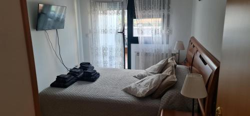 een slaapkamer met een bed, een televisie en een raam bij Marvic Llanes in Posada de Llanes