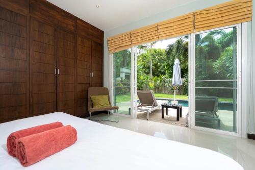 a bedroom with a white bed and a large window at Balinese Style 3BR Villa Morning Forest, Nai Harn in Rawai Beach