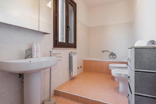 bagno con lavandino, servizi igienici e specchio di Casa Isola con Giardino by Wonderful Italy a Siracusa