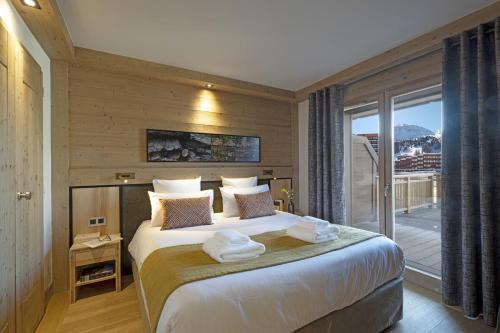 um quarto com uma cama grande e uma varanda em Résidence Manaka em Aime La Plagne