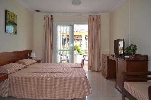 a hotel room with two beds and a television at Apartamentos Garden Atlantis en Club Atlantis in Adeje