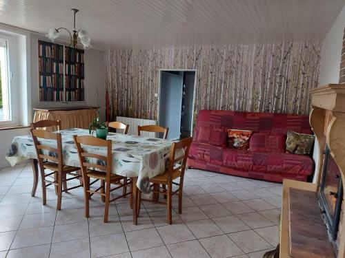 sala de estar con mesa y sofá rojo en La-Haut, gite-maison de vacances, en Poinson-lès-Fays