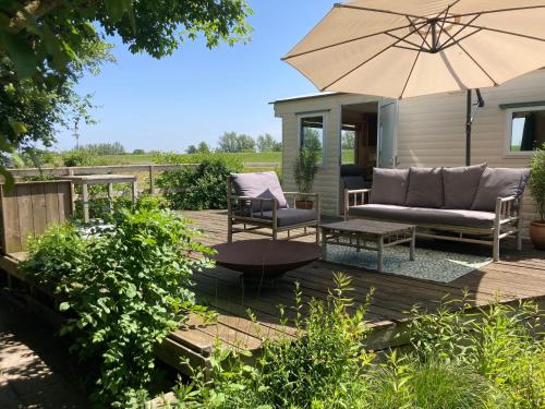 une terrasse avec un canapé et un parasol dans l'établissement Classic bungalow by the IJsselmeer, à Workum