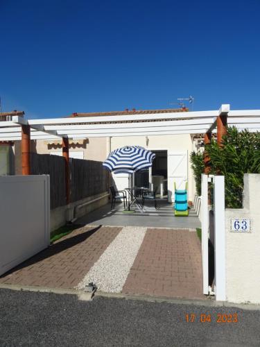 une terrasse avec un parasol bleu et blanc sur une maison dans l'établissement Maison cocooning à 1km de la mer, à Saint-Cyprien