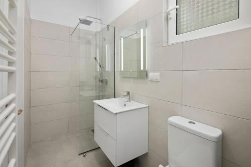 a white bathroom with a sink and a toilet at Karia Holiday Home in Lefkimmi