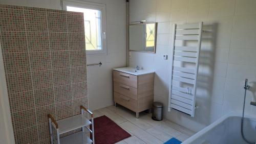 La salle de bains est pourvue d'une baignoire, d'un lavabo et d'une douche. dans l'établissement La Villa du Marensin, à Lit-et-Mixe