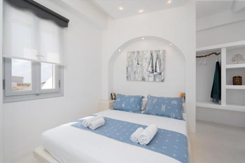 a white bedroom with a bed with blue sheets and pillows at Santorita Suites in Akrotiri