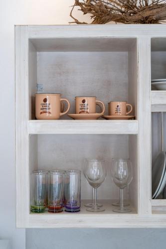 a shelf with cups and wine glasses on it at Santorita Suites in Akrotiri