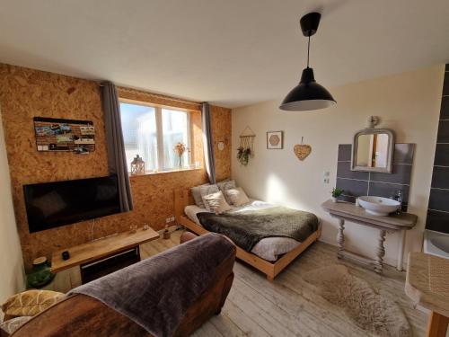 une chambre avec un lit, une télévision et un canapé dans l'établissement Le Garage, à Cussy