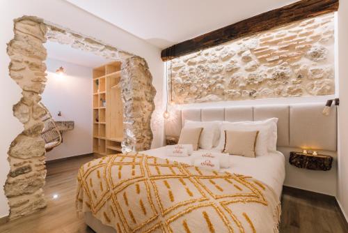a bedroom with a large bed and a stone wall at Casa do Tio Farinha by RNvillage in Sesimbra