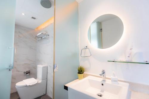 a white bathroom with a sink and a mirror at Hotel NuVe in Singapore