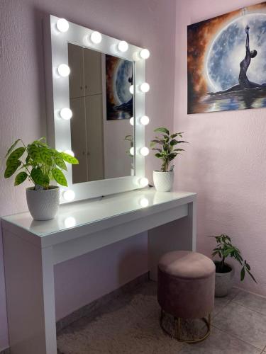 a bathroom with a vanity with a mirror and two plants at Ruby Apartment in Agios Nikolaos