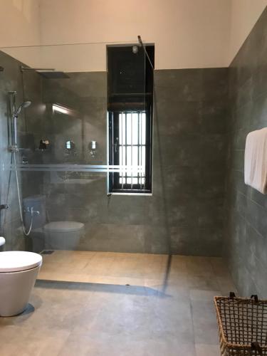 a bathroom with a shower and a toilet and a sink at The Postcard Galle in Galle